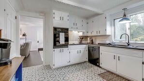 A modern kitchen with white cabinetry, a built-in oven, and a window with a pendant light. - Close to Connecticut College & Coast Guard Academy (Quaker Hill)