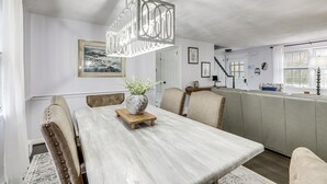 A dining area with a wooden table, upholstered chairs, and a hanging light fixture. - Close to Connecticut College & Coast Guard Academy (Quaker Hill)