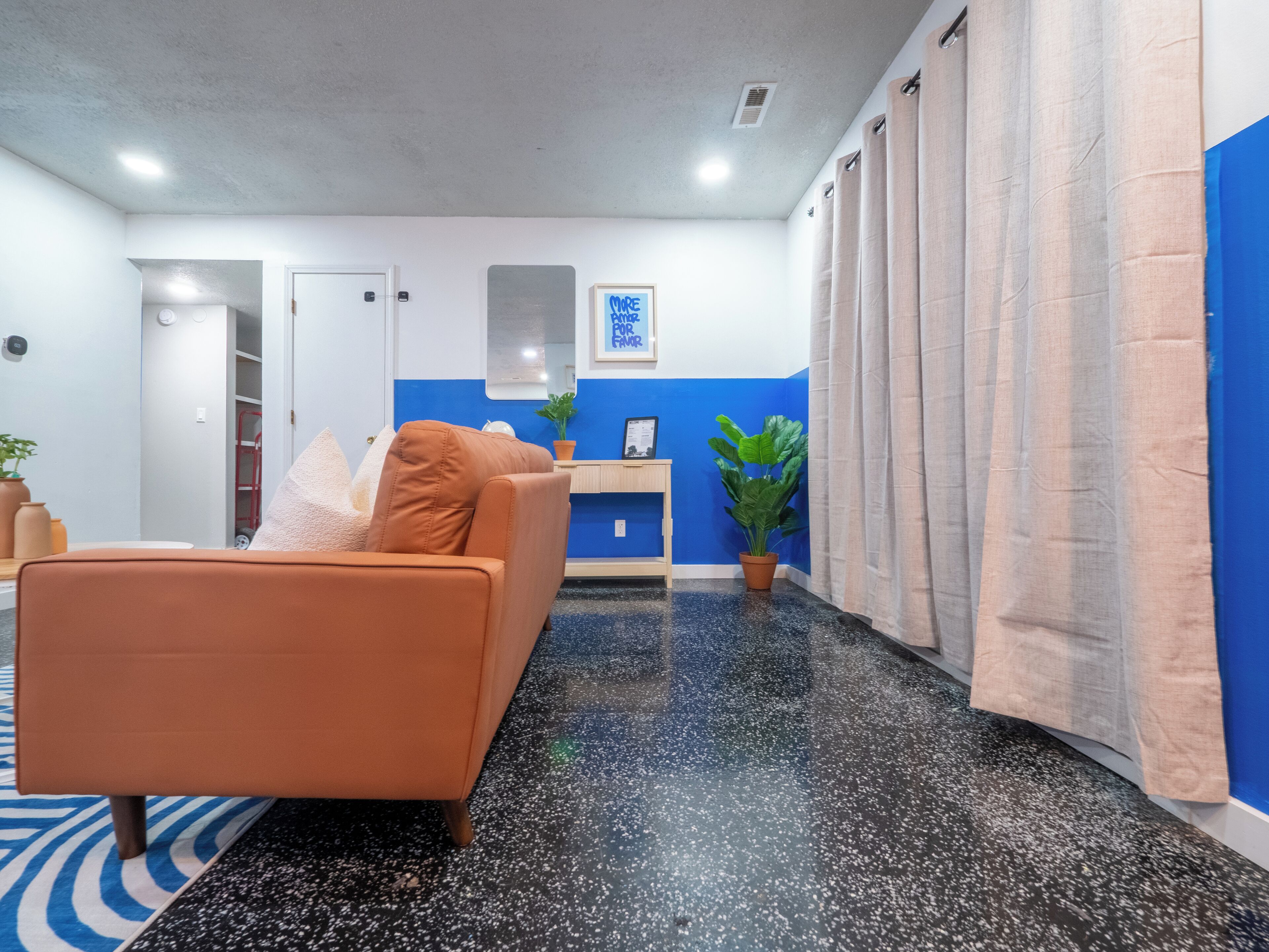 Quarto moderno com sofá, escrivaninha e planta em vaso.