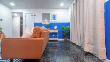 Quarto moderno com sofá, escrivaninha e planta em vaso.