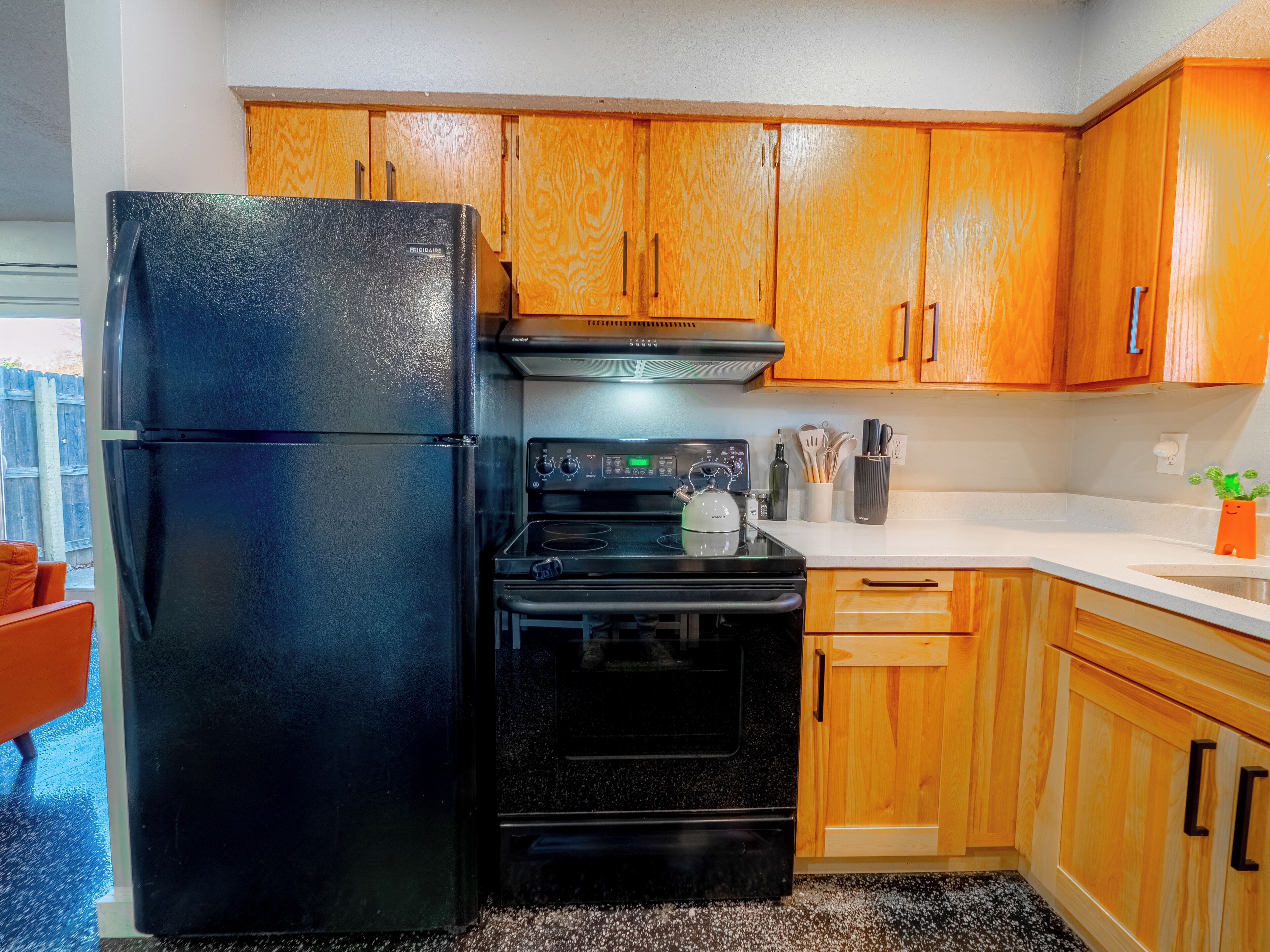 Una cocina con armarios de madera, un refrigerador negro, una estufa y un lavaplatos.