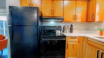 Una cocina con armarios de madera, un refrigerador negro, una estufa y un lavaplatos.