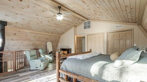 A bedroom with a wooden ceiling, a bed with a checkered blanket, two chairs, a wooden bench, and a small table. - Hot Tub & Views! 'Squatch’s Place' in Blairsville (Blairsville)