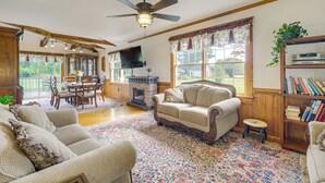 A cozy living room with a fireplace, a ceiling fan, and a bookshelf. - Walk to Dtwn Warsaw: Family Home w/ Deck! (Warsaw)