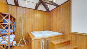 A wooden spa room with a hot tub, wooden shelves with towels, and a wicker chair. - Walk to Dtwn Warsaw: Family Home w/ Deck! (Warsaw)