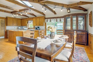 A spacious kitchen with wooden cabinets, a dining table set for four, and a large wooden cabinet with glass doors. - Walk to Dtwn Warsaw: Family Home w/ Deck! (Warsaw)