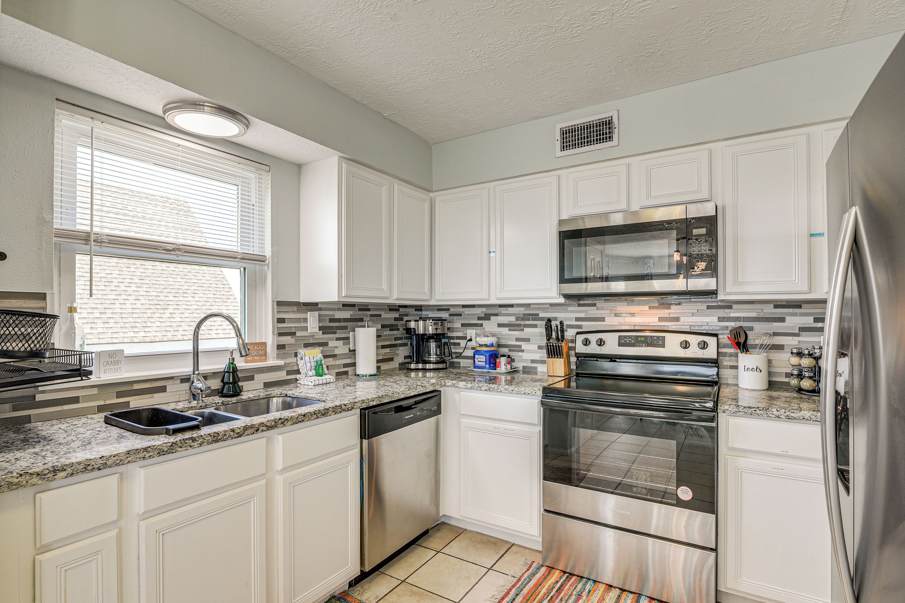A modern kitchen with white cabinetry, stainless steel appliances, and a tiled backsplash.