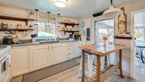A kitchen with white cabinets, a wooden table, and a hanging light fixture. - Lake Malone Cabin Getaway! Dock, Fire Pit, Grill (Dunmor)