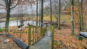 A wooden staircase leading to a dock over a calm lake, surrounded by trees and a grassy area. - Lake Malone Cabin Getaway! Dock, Fire Pit, Grill (Dunmor)