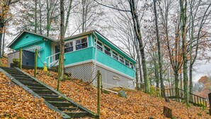 A turquoise building with a staircase leading up to it, surrounded by trees and fallen leaves. - Lake Malone Cabin Getaway! Dock, Fire Pit, Grill (Dunmor)