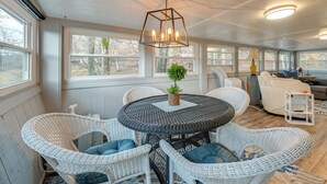 A covered outdoor seating area with a round table, white wicker chairs, and a hanging light fixture. - Lake Malone Cabin Getaway! Dock, Fire Pit, Grill (Dunmor)