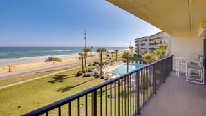 Ein Balkon mit Blick auf den Strand, ein Pool und eine Straße.