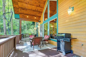 A covered outdoor deck with wooden flooring, wicker furniture, and a grill. - Fun w/ Family! Mtn-View Cabin w/ Deck in Sylva (Sylva)