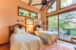A bedroom with two beds, a ceiling fan, a large window with a view of the outdoors, and a wooden deck outside. - Fun w/ Family! Mtn-View Cabin w/ Deck in Sylva (Sylva)
