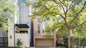 A modern building with a garage door, a small tree in the front yard, and a brick facade. - Uptown Dallas Group Getaway Near Art, Eats & More! (Dallas)