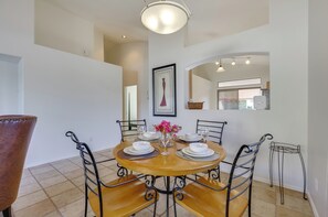 A dining area with a round wooden table, black metal chairs, and a vase with flowers. - Hike, Golf & Relax: Desert Retreat in Cave Creek (Cave Creek)