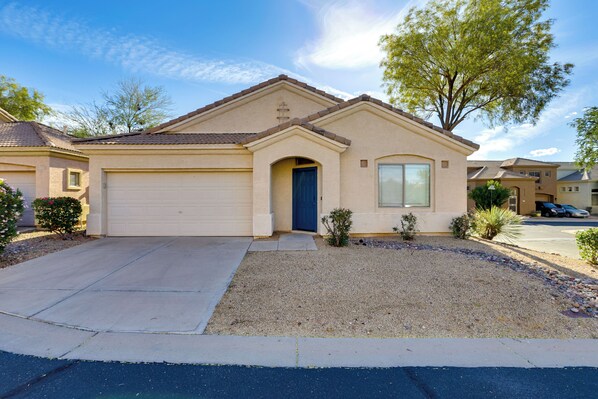 A single-story house with a garage, a front door, and a small front yard with gravel and a tree. - Hike, Golf & Relax: Desert Retreat in Cave Creek (Cave Creek)