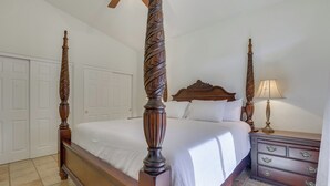 Una cama con dosel, un tablero de cabecera con lámpara y un aparador con cajones.