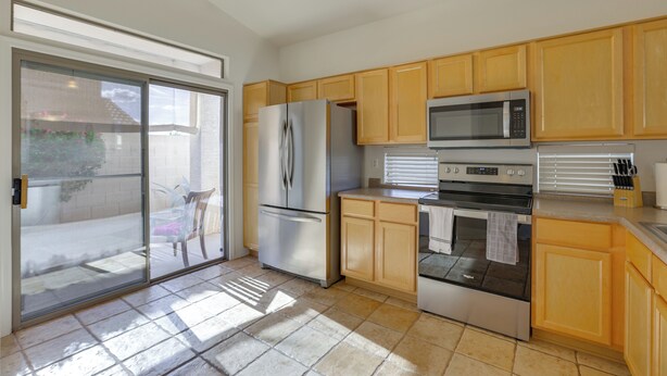 Una cocina moderna con refrigerador, microondas, horno y armarios de madera.