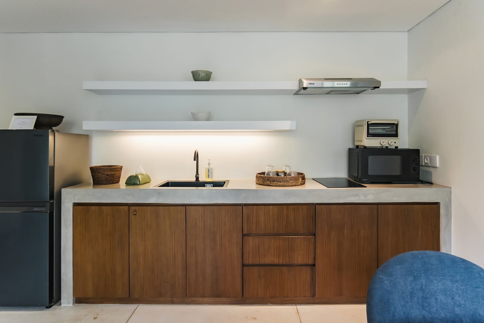 A modern kitchen with a built-in oven, microwave, and a small refrigerator.