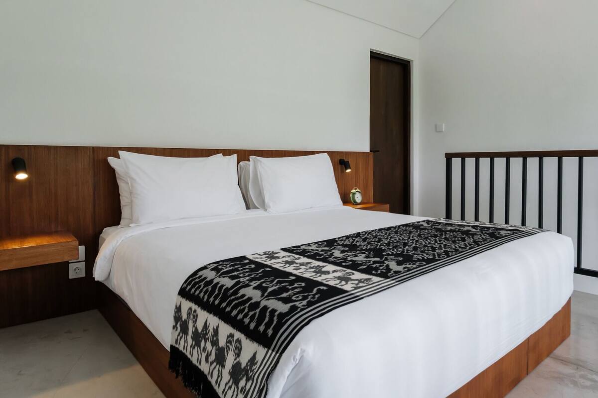 Una camera da letto con un letto, comodini, abat-jour e una porta.
