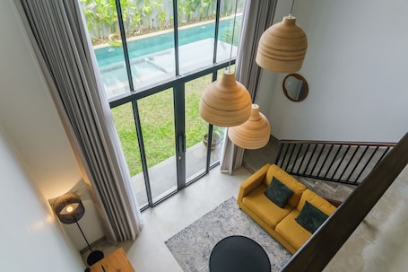 A modern interior with a yellow sofa, large windows, and a pool view.