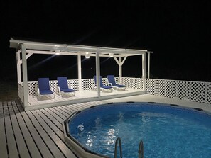 En pool med tak, solstolar och ett vitt staket.