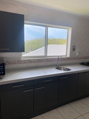 A kitchen with a window, a sink, and a stove. - Bendishon Villa - 5 Bedroom Villa (Grote Berg)