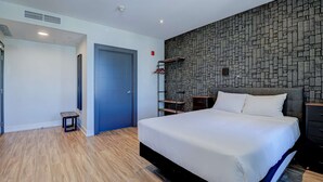 Una habitación de hotel moderna con una cama grande, un armario, una mesita y una pared con un diseño geométrico.