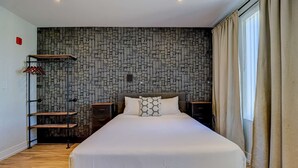 A hotel room with a large bed, a wardrobe, a shoe rack, and a patterned wall. - Dream Suites - Deluxe Queen Suite (MISSISSAUGA)