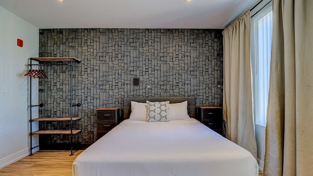 Una habitación de hotel con una cama grande, un armario, un zapatero y una pared con diseño.