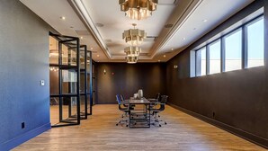 A conference room with a long table, black chairs, and a modern chandelier. - Dream Suites - Deluxe Family  Suite (MISSISSAUGA)