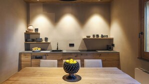Uma cozinha moderna com armários de madeira, uma ilha central com uma tigela de limões e luminárias pendentes.