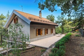 Ein modernes Haus mit Satteldach, Schornstein und überdachter Terrasse.