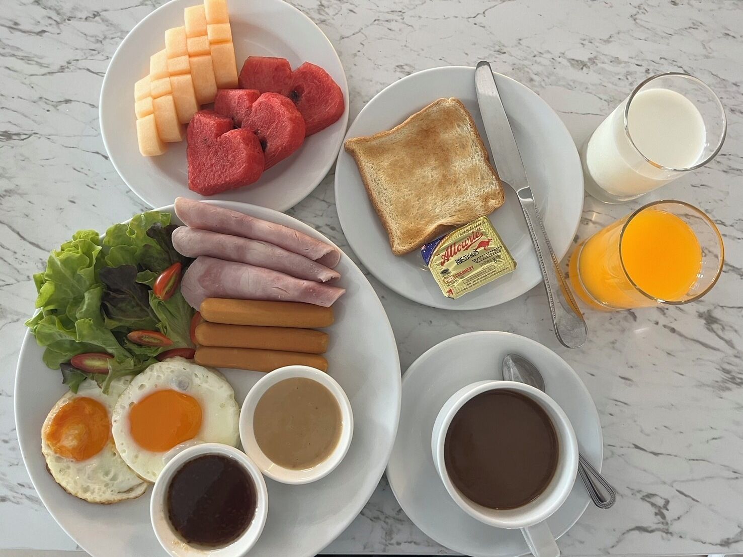Un plato de desayuno con tostadas, jamón, huevos y una ensalada.