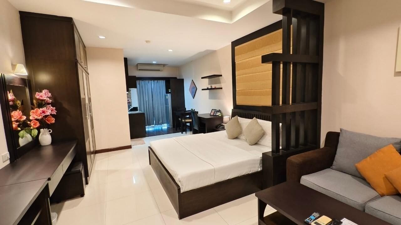 Una habitación de hotel moderna con una cama grande, un sofá, un escritorio y un armario.