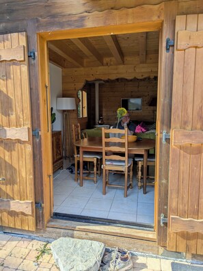 A wooden interior with a dining table and chairs, a television, and a lamp. - French Mountain Chalet in Morzine area (Essert Romand) (Essert-Romand)