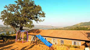 A playground with a slide, swings, and a tree. - Cosmicstays Birdsong Lakeview Cottage  (Velhe)