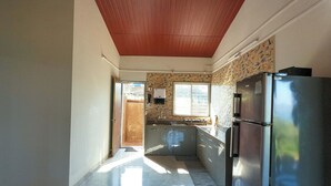 A kitchen with a wooden ceiling, a stainless steel refrigerator, and a window with patterned wallpaper. - Cosmicstays Birdsong Lakeview Cottage  (Velhe)