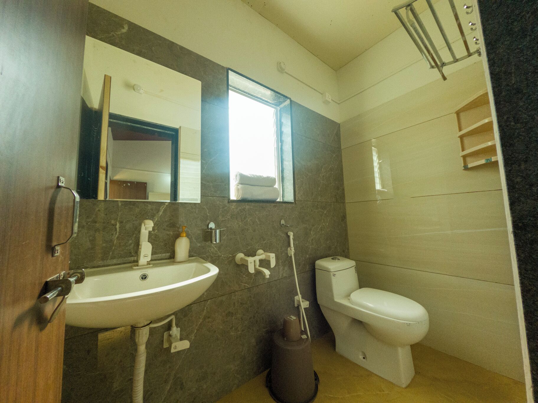 A bathroom with a sink, mirror, toilet, and towel rack.