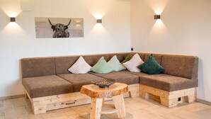 Een moderne woonkamer met een bruine hoekbank, een houten salontafel en decoratieve kussens.