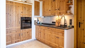 Een keuken met houten kastjes, een inbouwoven en een spoelbak met een moderne kraan.