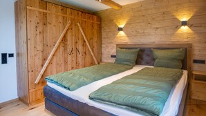 Een kamer met houten lambrisering, een bed, twee wandlampen en een houten garderobe.