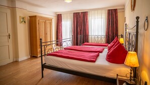 Ein Schlafzimmer mit Bett, Holzschrank, Vorhängen und einer Lampe.