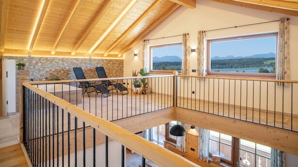 Un loft espacioso con techo alto, pared de piedra y balcón con vistas a un paisaje montañoso.