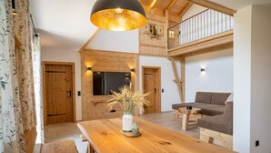 Un salón espacioso con una mesa de madera, un sofá y una escalera que sube a un nivel superior.