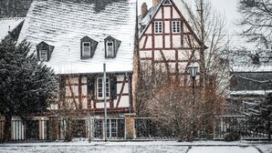 Une maison traditionnelle à colombages, dotée d’un toit à forte pente, de nombreuses fenêtres et d’une cheminée bien visible.