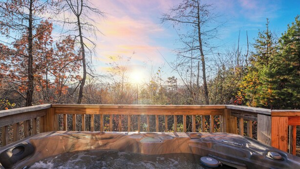 A hot tub surrounded by a wooden deck with a forest backdrop. - Whisper Cabin: Hot Tub, Game Loft, Open Living, Minutes to Downtown Gatlinburg (Gatlinburg)