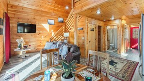A wooden cabin interior with a living area, a staircase, and a dining space. - Whisper Cabin: Hot Tub, Game Loft, Open Living, Minutes to Downtown Gatlinburg (Gatlinburg)