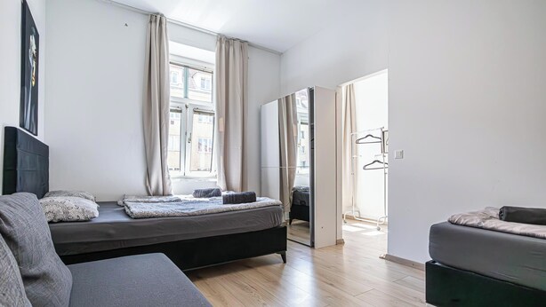 Een moderne slaapkamer met een bed, een slaapbank, een kledingkast en een spiegel.